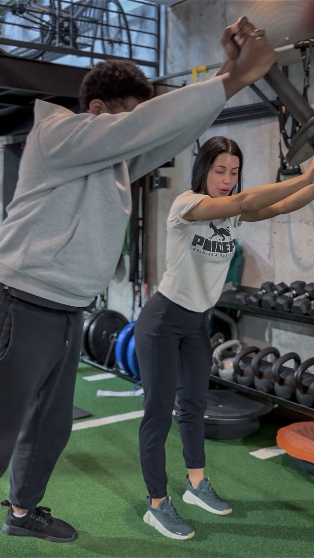PrideFit coach hands-on cueing an overhead press